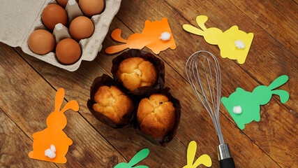 Homemade muffin with paper rabbits. Muffin and eggs on a wooden background