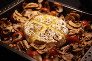 Camembert baked.Cheese with mushrooms and tomatoes in a baking sheet.Baked Camembert cheese with vegetables