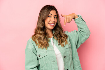 Fototapeta premium Young caucasian woman isolated person pointing by hand to a shirt copy space, proud and confident