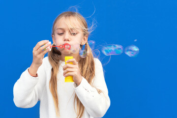 Funny girl blowing soap bubbles. High quality photo