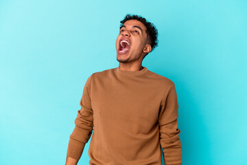 Young african american curly man isolated on blue shouting very angry, rage concept, frustrated.