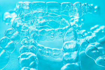 Invisible dental teeth brackets tooth aligners on turquoise background. Plastic braces dentistry retainers to straighten teeth.