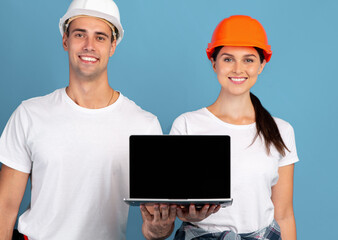 Happy Young Man And Woman In Hardhats Holding Laptop With Black Screen