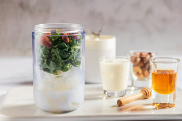 Healthy green kale smoothie in portable blender mixed greek yogurt, almond and honey on white table background. Kale is considered a superfood because it's a great source of vitamins and minerals.