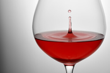 A drop of wine in a glass on a light background