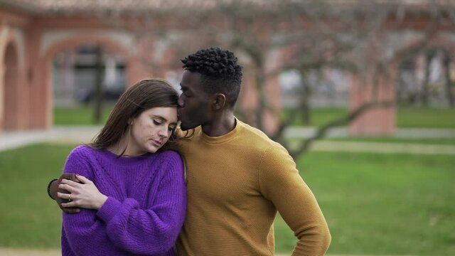 Friend kissing depressed girlfriend in forehead while walking outside together coping and mourning