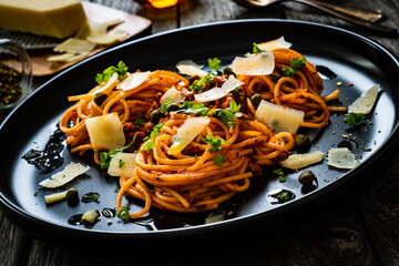 Spaghetti a'la bolognese with minced pork meat and parmesan on wooden table