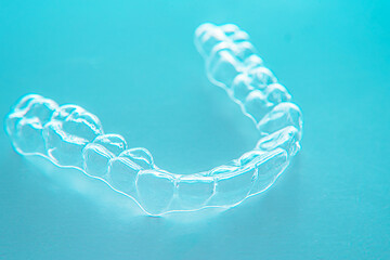Invisible dental teeth brackets tooth aligners on turquoise background. Plastic braces dentistry...