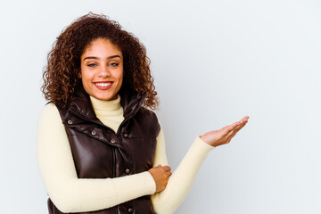 Young african american woman isolated on white background showing a copy space on a palm and holding another hand on waist.