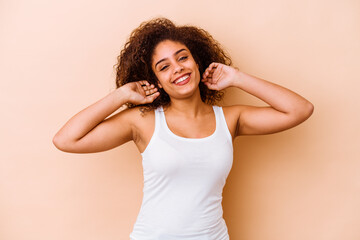 Young african american woman isolated on beige background stretching arms, relaxed position.