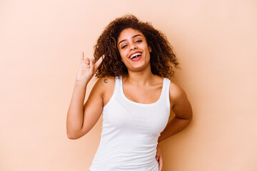Fototapeta premium Young african american woman isolated on beige background showing a horns gesture as a revolution concept.