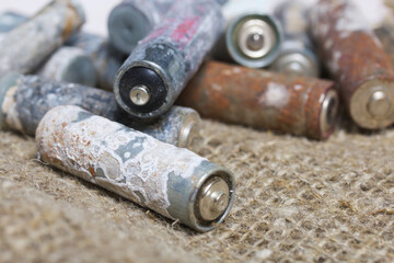 Corroded used batteries. Nearby is linen. Close-up shot.