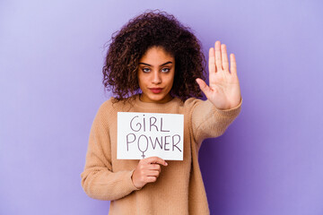 Young African American woman holding a Girl power placard isolated on purple background standing with outstretched hand showing stop sign, preventing you.