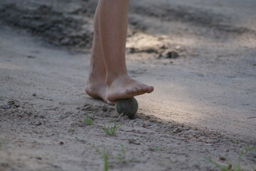 The child plays ball with bare feet. Belarusian village.
