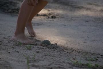 The child plays ball with bare feet. Belarusian village.
