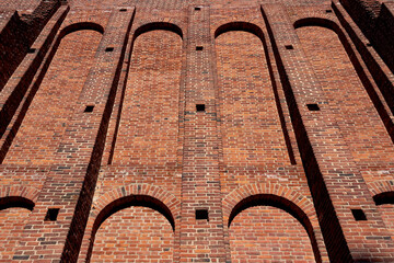 A wide old brick wall with recesses and protruding parts.