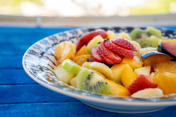 Natural and healthy fruit salad with orange set in a vintage plate on a rustic blue surface. Healthy Food Concept, Healthy Life.
