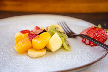 Natural and healthy fruit salad with orange set in a gourmet presentation plate on a rustic black surface. Healthy Food Concept, Healthy Life.
