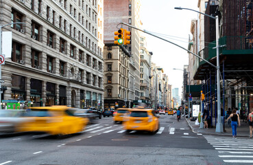 Yellow taxis driving down the street on Fifth Avenue through the busy intersections in Midtown...