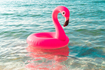 Hello summer. Pink inflatable flamingo in blue ocean water for sea summer beach background. Trendy summer concept.