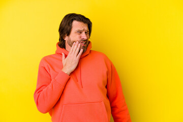 Middle age caucasian man isolated on yellow background having a strong teeth pain, molar ache.