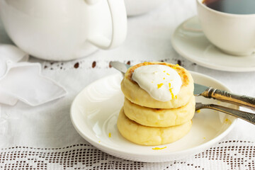 Cottage cheese pancakes with sour cream and lemon zest, served with tea.