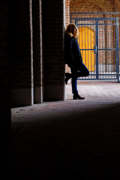 Stockholm, Sweden A Woman Leans Against An Archway In An Outdoor Corridor At The Stockholm Stadion Olympic Stadium.