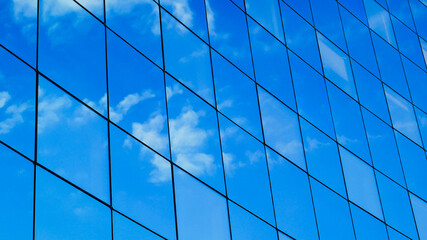 transparent glass wall of office building, sky and clouds reflecting 