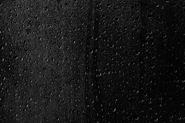 Drops of water flow down the surface of the clear glass on a black background. Texture for creativity. - obrazy, fototapety, plakaty