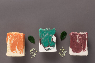 wellness and spa composition with natural herbal soap bars on gray background with leaves and sea salt. Diy cosmetic products. copy space