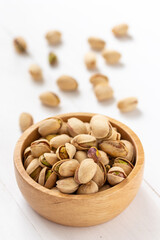 Pistachio nuts in a wooden bowl on white background