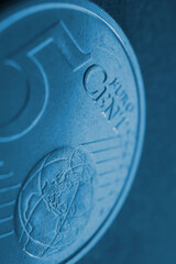 A 5 euro cent coin close-up. Dark blue vertical background about money, economy or finance of countries of the European community. Backdrop or wallpaper. Macro