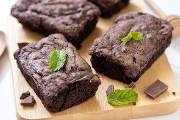 Top view of chocolate brownies on wooden board on white table, homemade sweet and dessert concept