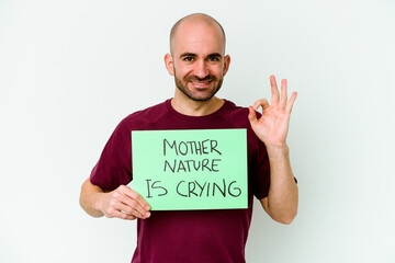 Young caucasian bald man holding a Mother Nature crying isolated on white background cheerful and confident showing ok gesture.