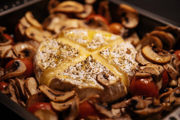 Camembert baked.Cheese with mushrooms and tomatoes in a baking sheet.Baked Camembert cheese with...