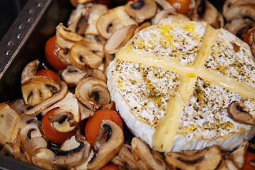 Camembert baked.Cheese with mushrooms and tomatoes in a baking sheet.Baked Camembert cheese with vegetables