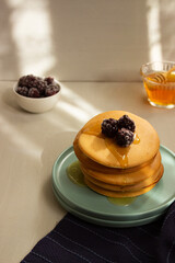 Pancakes on turquoise plate with honey and blackberries. Breakfast. Meal.