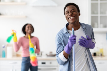 Black guy having fun with his girlfriend while cleaning kitchen