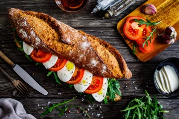 Foto op Plexiglas Snackbar Caprese sandwich with tomato, mozzarella and arugula on wooden table