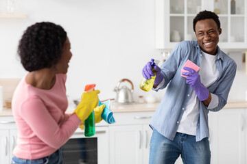 Joyful african american couple shooting with cleaning sprays