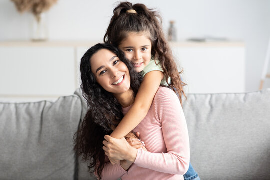 Portraif Of Cute Little Girl And Her Mom Embracing At Home