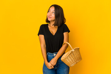Young mixed race woman holding a basket dreaming of achieving goals and purposes
