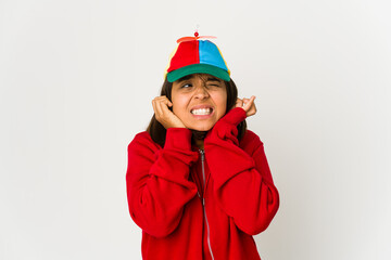 Young hispanic woman wearing a cap with propeller isolated covering ears with hands.