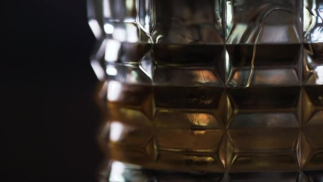 
149 Panorama of the edge of a glass into which a liquid, cocktail or lemonade is poured and which shines beautifully in the light in slow motion
