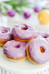 Obraz na płótnie Canvas Homemade Purple donuts on dessert stand with Spring flowers