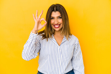 Young indian woman isolated on yellow background cheerful and confident showing ok gesture.