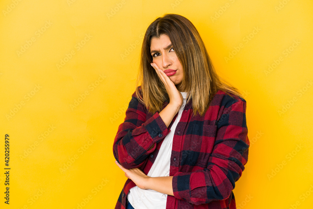 Wall mural young indian woman isolated on yellow background contemplating, planning a strategy, thinking about 