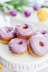 Homemade Purple donuts on dessert stand with Spring flowers
