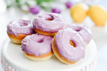 Homemade Purple donuts on dessert stand with Spring flowers