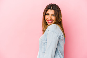 Fototapeta premium Young indian woman isolated on pink background looks aside smiling, cheerful and pleasant.